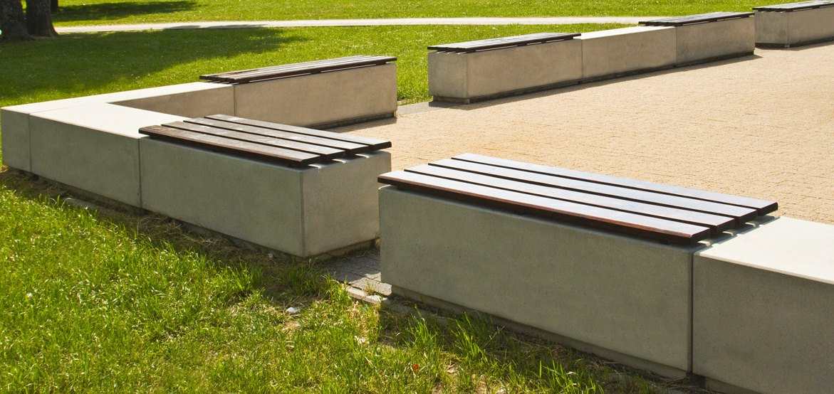 Ławka z betonu architektonicznego z wygodnym drewnianym siedziskiem bez oparcia, wykonana przez producenta betonowych mebli miejskich. 